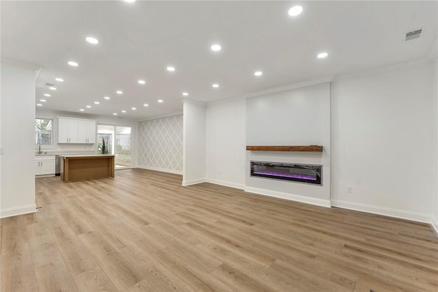 unfurnished living room with crown molding, sink, and light hardwood / wood-style flooring