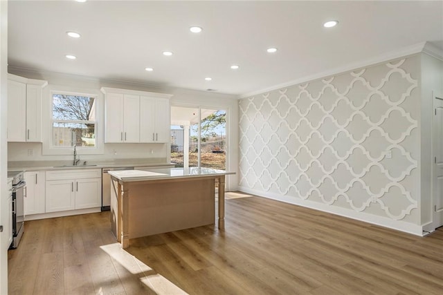 kitchen with sink, light hardwood / wood-style flooring, white cabinets, and a kitchen island