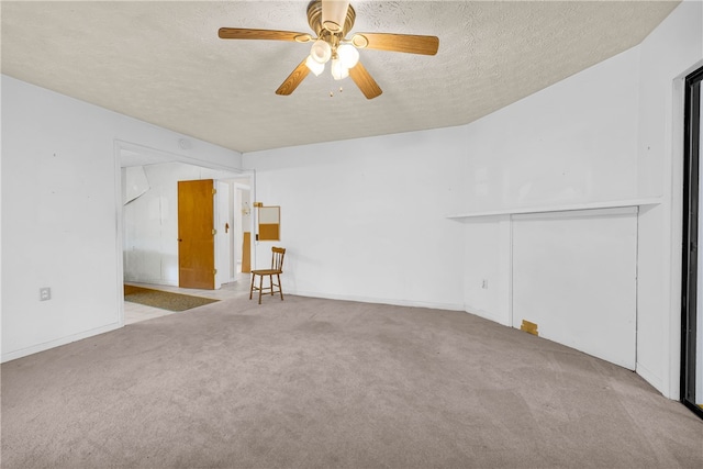 empty room with ceiling fan, light colored carpet, and a textured ceiling