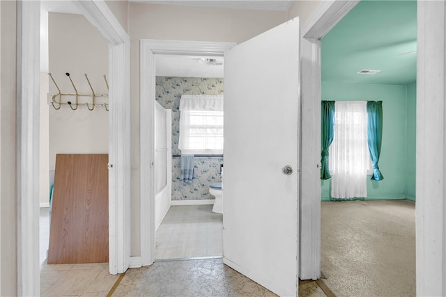 hallway with plenty of natural light and light carpet