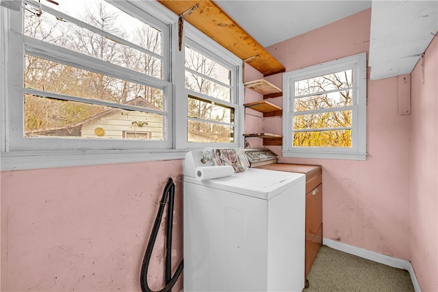 laundry area featuring light colored carpet, washing machine and dryer, and a healthy amount of sunlight