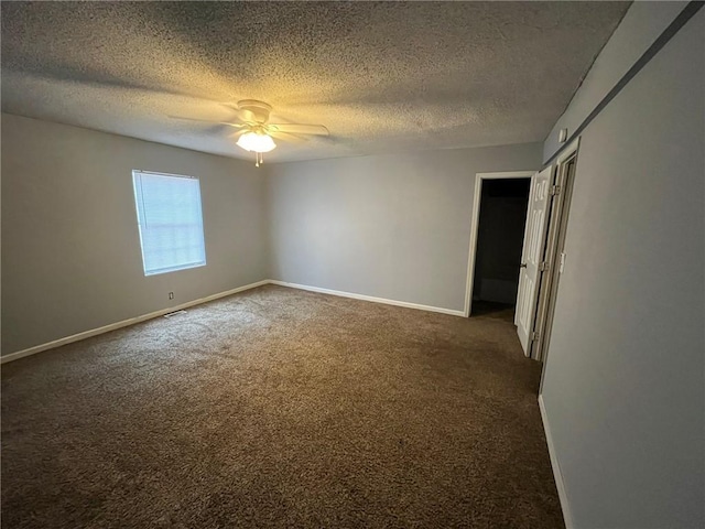 empty room featuring dark colored carpet, ceiling fan, and a textured ceiling