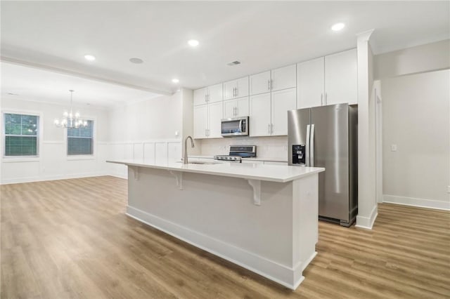 kitchen with sink, white cabinetry, a center island with sink, a kitchen breakfast bar, and stainless steel appliances