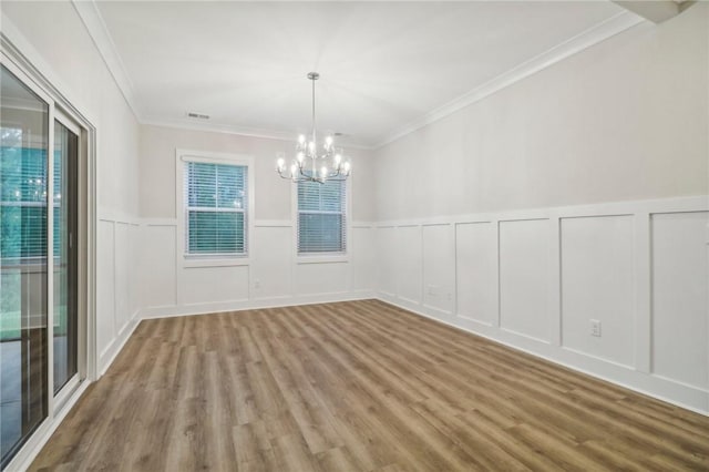 unfurnished dining area with a notable chandelier, ornamental molding, and light wood-type flooring