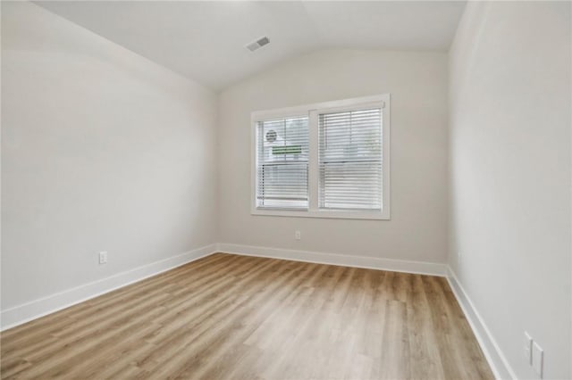 unfurnished room featuring lofted ceiling and light hardwood / wood-style flooring