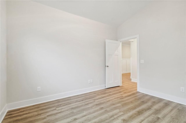 unfurnished room with vaulted ceiling and light wood-type flooring