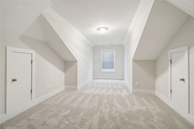 bonus room with lofted ceiling and light colored carpet