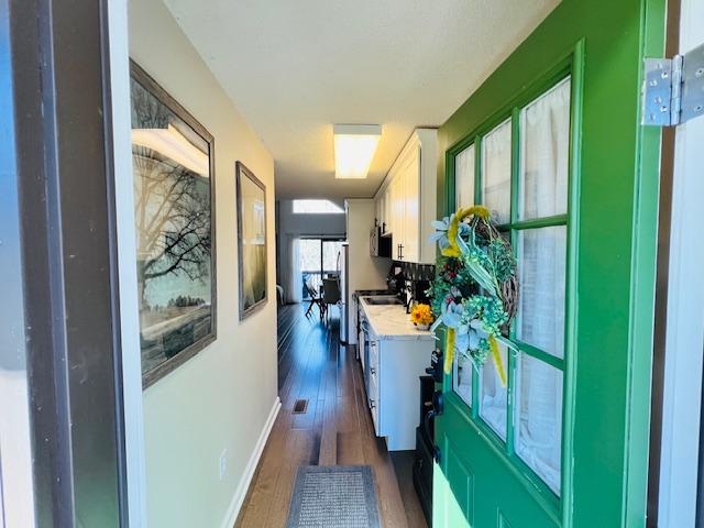 hall featuring dark wood-style floors and baseboards