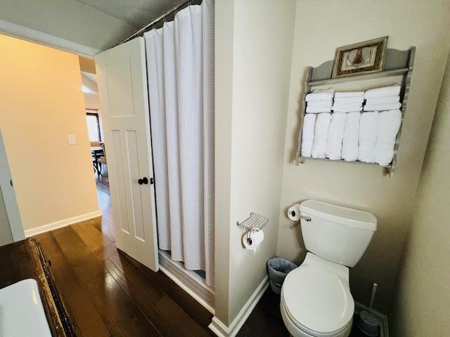 bathroom with hardwood / wood-style flooring, toilet, and a shower with curtain