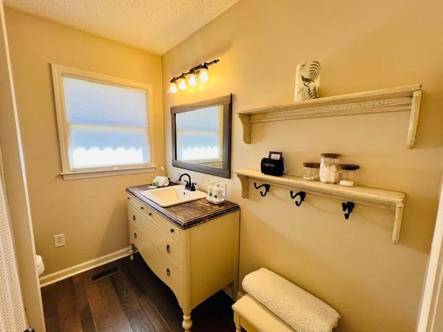 bathroom featuring toilet, vanity, a textured ceiling, wood finished floors, and baseboards