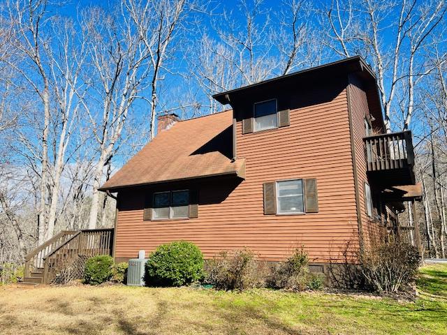 view of home's exterior featuring a chimney, central AC unit, and a yard