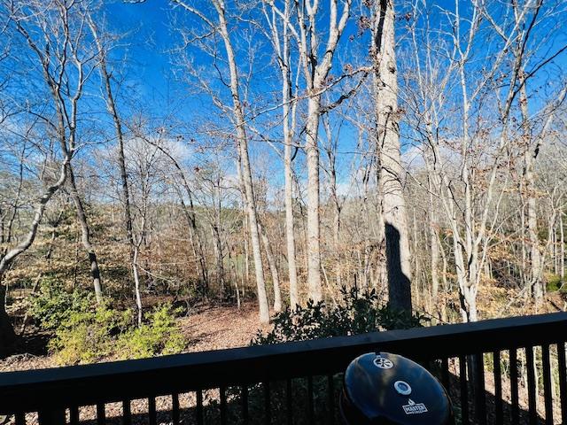 view of yard with a balcony and a view of trees