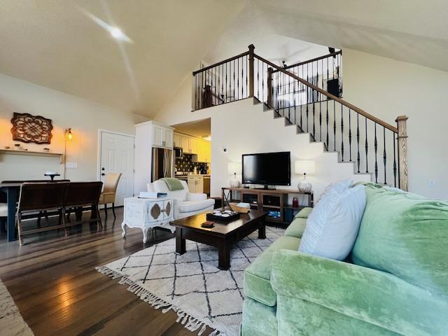 living area featuring light wood-style floors, high vaulted ceiling, and stairway