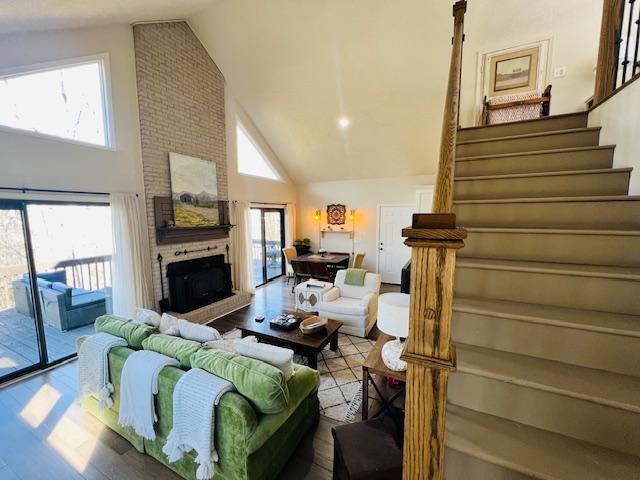 living room featuring a fireplace, high vaulted ceiling, and light hardwood / wood-style flooring