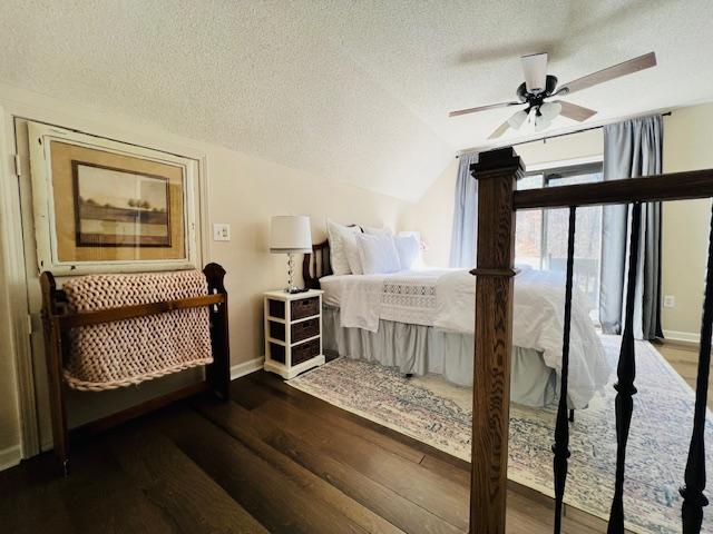 bedroom featuring a textured ceiling, baseboards, wood finished floors, and lofted ceiling