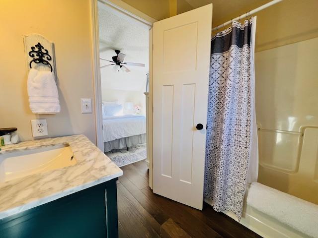 full bathroom featuring curtained shower, ceiling fan, vanity, and wood finished floors