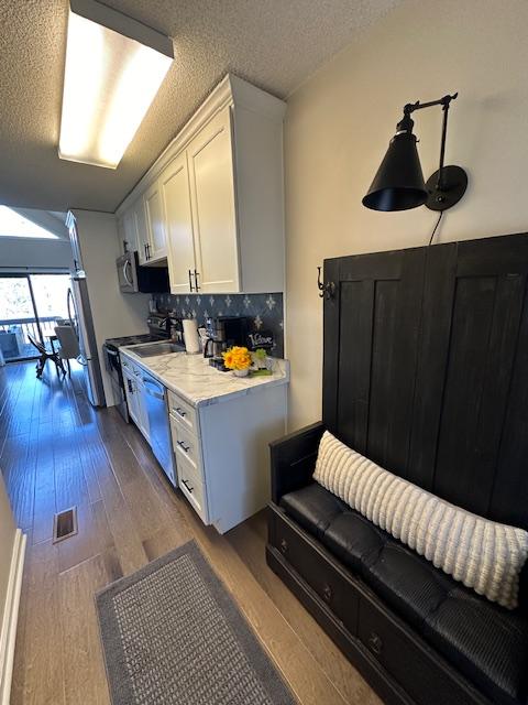 kitchen featuring dark wood finished floors, stainless steel appliances, visible vents, backsplash, and white cabinets