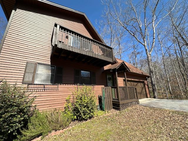 view of side of property featuring an attached garage and a balcony