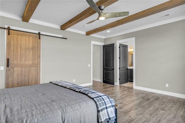 bedroom featuring ensuite bath, a barn door, ceiling fan, and hardwood / wood-style flooring