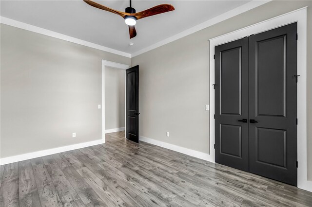 unfurnished bedroom with crown molding, light hardwood / wood-style flooring, a closet, and ceiling fan