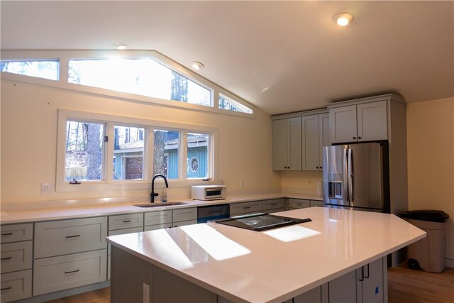 kitchen featuring sink, stainless steel fridge, a center island, and vaulted ceiling