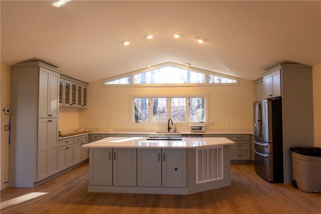 kitchen featuring lofted ceiling, gray cabinetry, a kitchen island, stainless steel fridge with ice dispenser, and light wood-type flooring