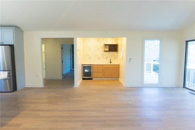 24 Mainsail Dr, Salem, SC 29676 - unfurnished living room featuring wine cooler, baseboards, bar area, and light wood-style floors