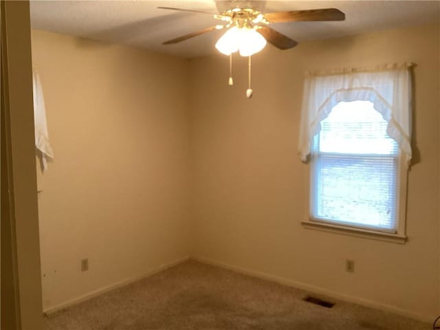 carpeted spare room featuring ceiling fan and a healthy amount of sunlight