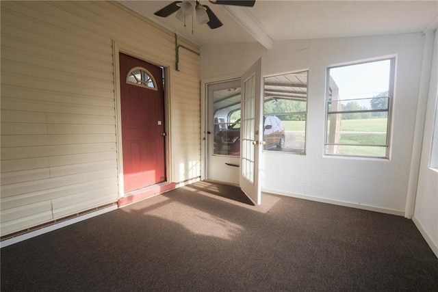 carpeted foyer with ceiling fan, lofted ceiling with beams, and wood walls