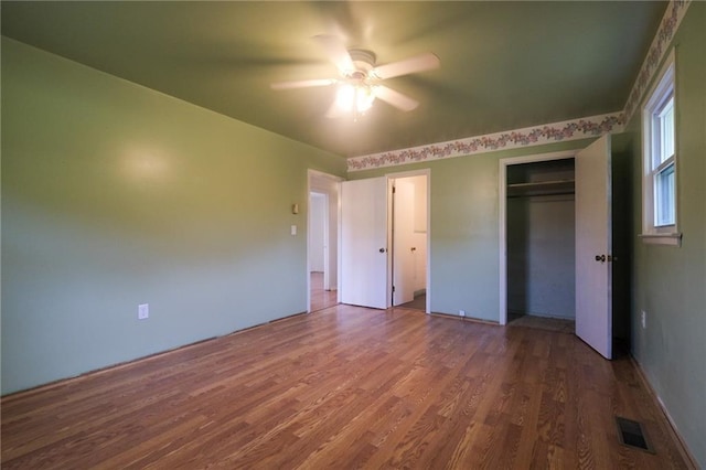 unfurnished bedroom with hardwood / wood-style floors, a closet, and ceiling fan