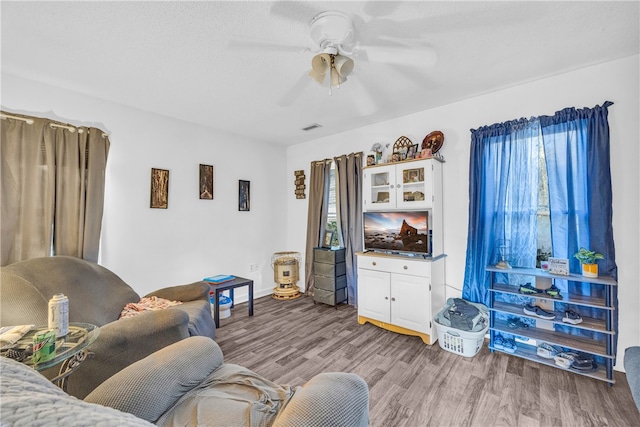 living room featuring wood-type flooring, ceiling fan, and plenty of natural light