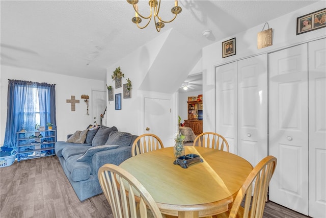 dining room with hardwood / wood-style floors, a notable chandelier, and a textured ceiling