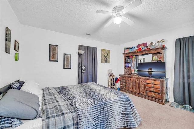 carpeted bedroom with ceiling fan and a textured ceiling