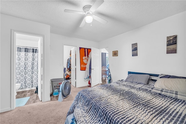 bedroom featuring ceiling fan, connected bathroom, light colored carpet, and a textured ceiling