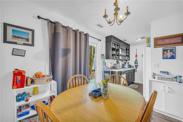 dining room with an inviting chandelier, wood-type flooring, and a textured ceiling