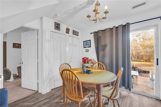 dining area featuring an inviting chandelier, hardwood / wood-style floors, and a textured ceiling