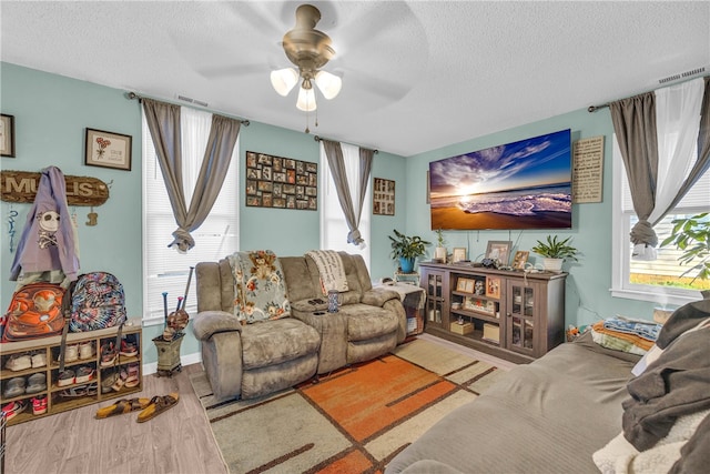 living room featuring ceiling fan, light hardwood / wood-style floors, and a textured ceiling