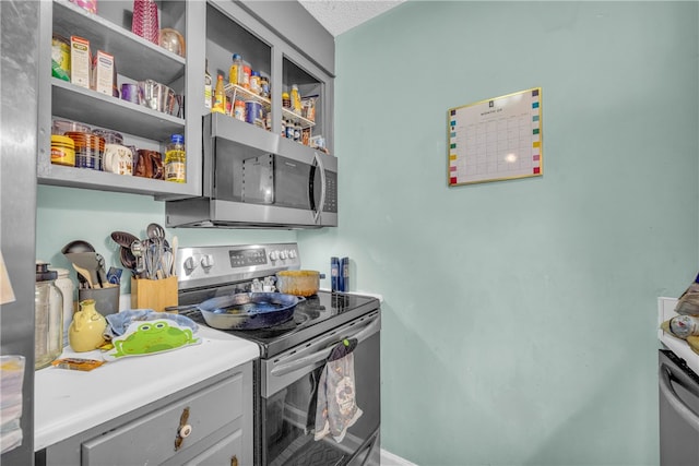 kitchen featuring stainless steel appliances, a textured ceiling, and gray cabinetry