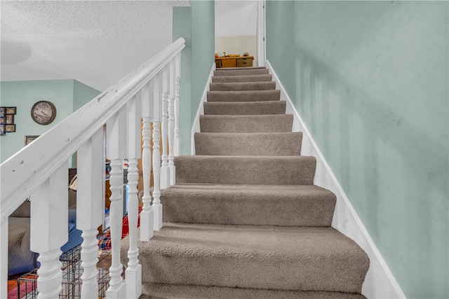 staircase featuring a textured ceiling