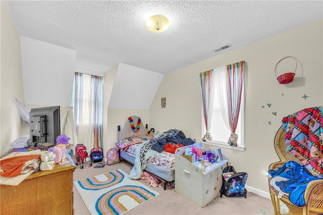 carpeted bedroom with vaulted ceiling and a textured ceiling