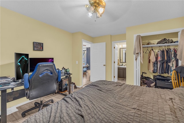 bedroom with light hardwood / wood-style flooring, ceiling fan, connected bathroom, a textured ceiling, and a closet