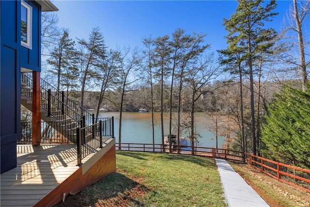 exterior space with stairs, a water view, and fence