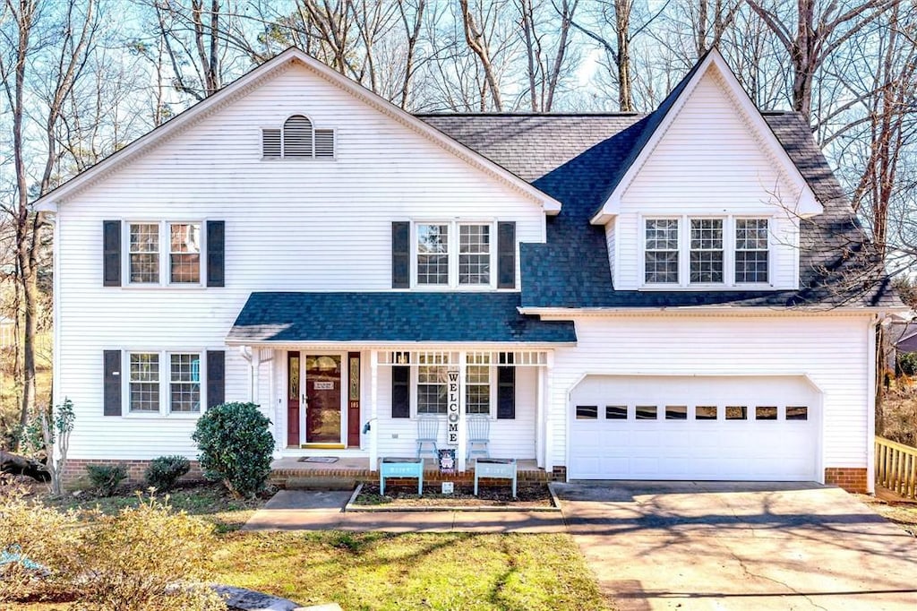 view of front of house with a porch, roof with shingles, and driveway