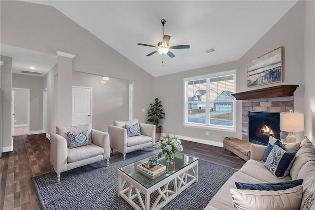 living room with dark wood-type flooring, ceiling fan, lofted ceiling, and a stone fireplace