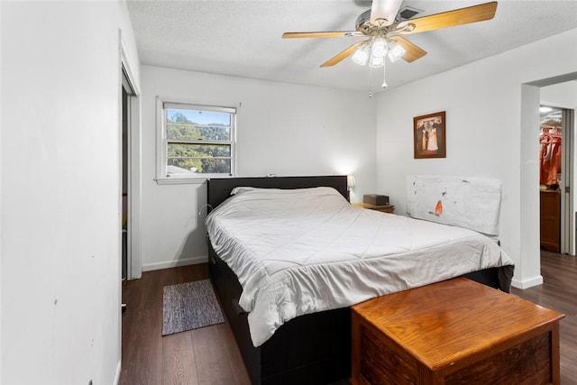 bedroom featuring dark hardwood / wood-style flooring, a textured ceiling, ceiling fan, and a closet