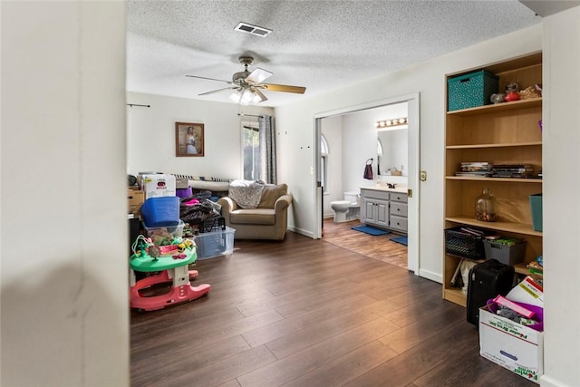 recreation room with dark hardwood / wood-style floors, a textured ceiling, and ceiling fan