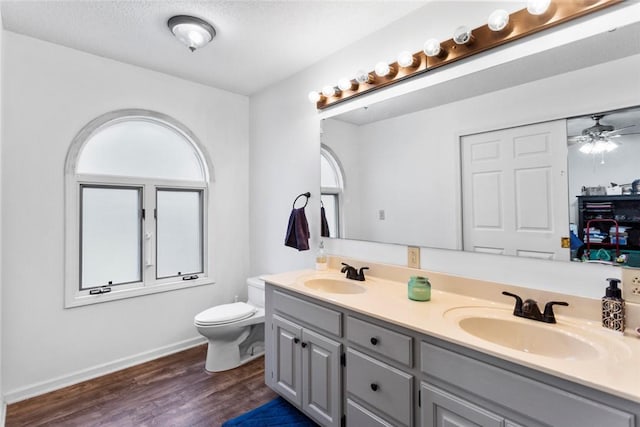 bathroom featuring hardwood / wood-style floors, vanity, ceiling fan, toilet, and a textured ceiling