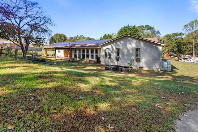 rear view of property with a lawn and solar panels