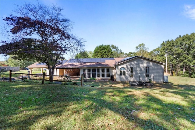 rear view of property with a yard and solar panels