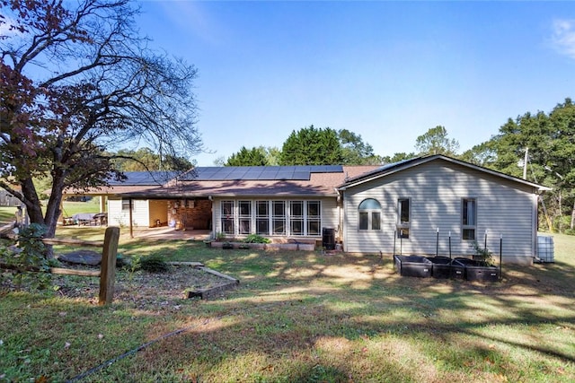 back of property featuring a yard and solar panels